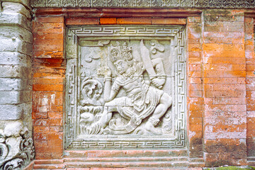 Ancient Stone Relief Depicting a Mythological Warrior in a Decorative Recess on a Temple Wall
