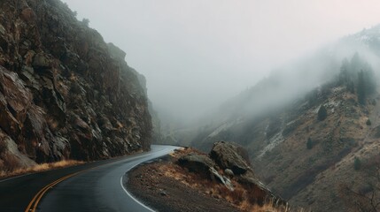 Winding mountain road disappearing into thick fog and mist