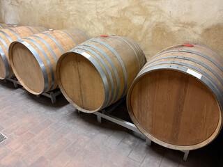 Row of traditional oak barrels in a rustic wine cellar, used for aging fine wine in a European vineyard, showcasing artisanal winemaking techniques