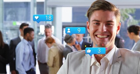 Smiling man wearing gray suit standing in office lobby, with digital social media icons, copy space