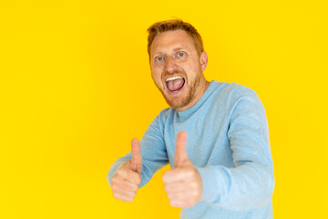 Excited redhead man showing thumbs up with both hands, expressing positivity and approval on a...