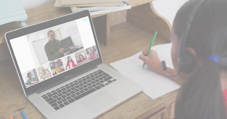 Writing child wearing red top, headset at home desk using green pen beside laptop, copy space