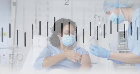 Masked patient receiving injection on hospital bed in clinic with syringe, IV stand, monitor