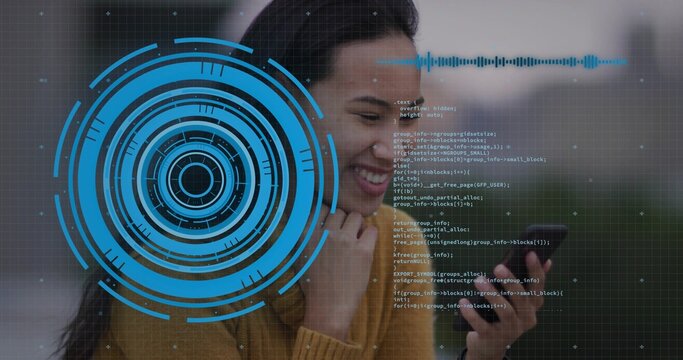 Smiling woman wearing mustard sweater interacting with smartphone in park, with holographic UI code