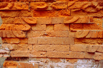 Close-up of ancient weathered brick wall texture with ornate decorative details and signs of age and erosion