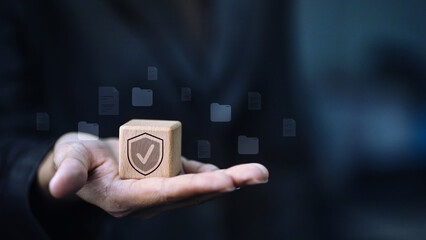 Cybersecurity trust and data protection concept, businessman holding wooden block with shield check icon