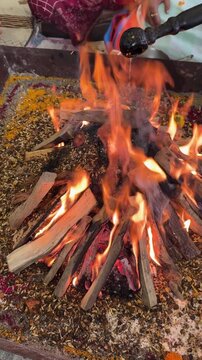 Pouring ghee with a wooden spoon in flames in havan kund in puja havan ceremony in hindu religion