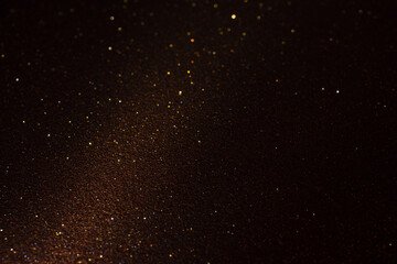 Dark brown micro textured surface with golden glitter and diagonal light beam from lower left highlighting grain, subtle sparkles reveal tactile relief and depth