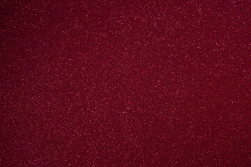 Bright burgundy glitter texture with fine granular relief, macro focus across surface reveals countless sparkles glowing vividly in elegant abstract style