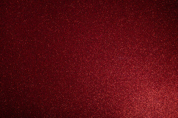 Deep red glitter surface glowing with soft light from lower right, macro focus highlights fine sparkles scattered evenly across textured abstract frame