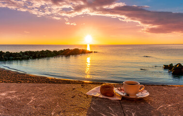 cup of coffee or tea with croissant on a morning embarkment beach with blue sea and beautiful...