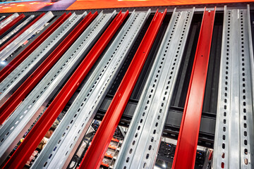 Abstract close-up of industrial shelving rails, featuring striking red and silver metal bars with perforated details. Modern architectural element for warehouse, logistics, or construction concepts.