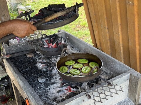 A traditional Malaysian dessert, Akok Bakar, being freshly baked over hot charcoal. The smoky aroma and glowing embers capture the authentic charm of heritage cooking passed down through generations.