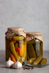 Two glass jars of pickled cucumbers with carrots and bell peppers.