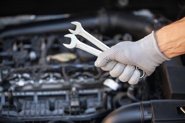 Hand mechanic with wrench on car background