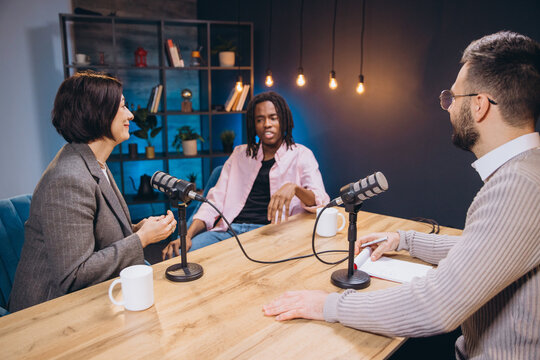 Content creators interviewing a guest in a podcast studio, discussing and recording audio content for their online audience