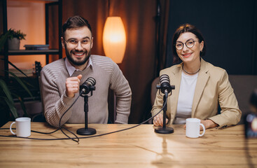 Podcasters engaging in lively conversation while recording a new episode in a professional studio filled with advanced audio equipment