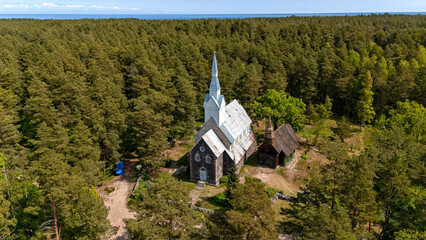 Historical church amidst lush forests on Ruhnu Island, Estonia, during sunny weather