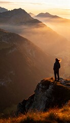 Fototapeta premium Silhouette of hiker at mountain peak during misty sunrise or sunset. 