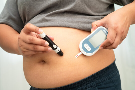 Asian woman injecting herself diabetes injecting insulin in stomach at home.