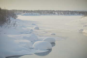 Freezing river with round snowdrifts and steam, close-up. Frosty day, northern winter landscape