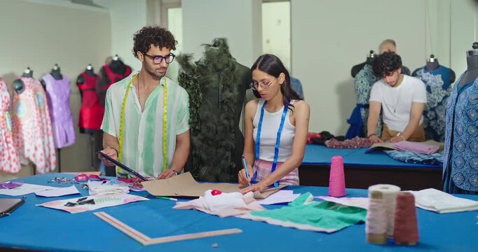 Indian young adult gen z female male man wear tape around neck use tab look screen talk share idea class room place. Tailor girl boy hold pencil do paper pattern create cloth craft dress learn work
