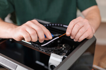 Close-up of hands cutting plastic tube with wire cutters during 3D printer assembly, concept of precision and manual work.