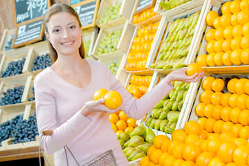 a woman is holding the oranges