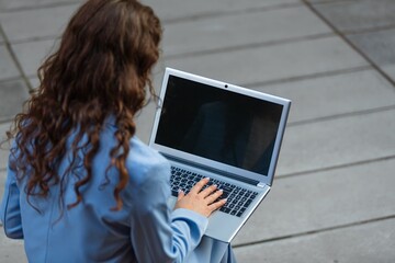 Business woman working on a laptop siting on outdoor