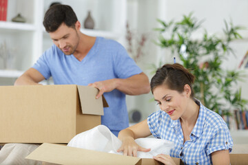 man hanging lamp while smiling woman unpacking stuff from boxes