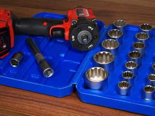 A set of metal splined wrench sockets of increasing sizes in a plastic case, which fit onto the power tool alongside.