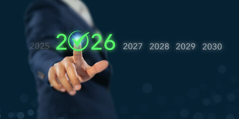 Setting future business goals in 2026. A businessman touches a glowing green 2026 with a check mark...