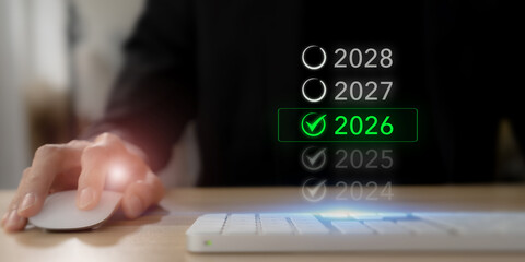 Setting future business goals in 2026. Using a computer mouse beside a glowing green check mark on 2026  in a list of years, symbolizing vision, strategic choice and business planning.