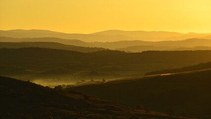 Dim light of dawn in the valleys of Transylvania. Silhouettes of mountains and hills.