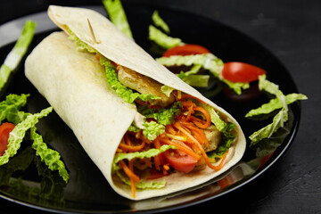 Freshly made wrap filled with grilled chicken, lettuce, and carrots, garnished with cherry tomatoes, served on a black plate, showcasing vibrant colors and appetizing presentation
