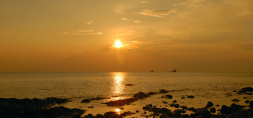 Beautiful atmospheric sunset with warm orange and pink hues, illuminating the sky and landscape in soft glowing light.
