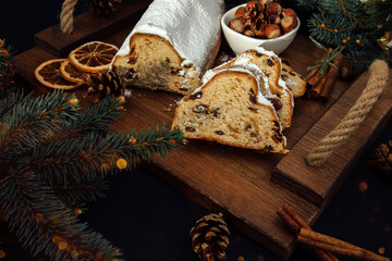 Christmas stollen on a wooden board with green branches of a Christmas tree. Christmas background, Christmas desserts