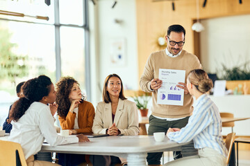 Team Presents Monthly Sales Report To Colleagues In Modern Office During Business Meeting