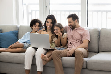 Family with siblings spend time at home with laptop