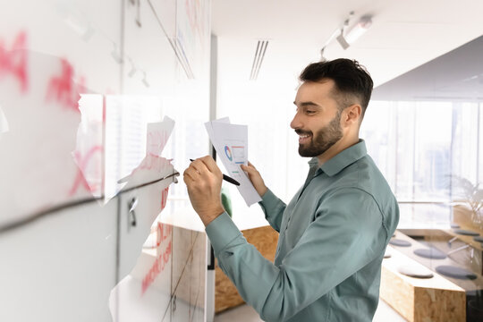 Fototapeta Young businessman engaged in planning using marker on glass board