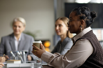 Young Adult Black Woman Smiling While Holding Coffee during Business Meeting