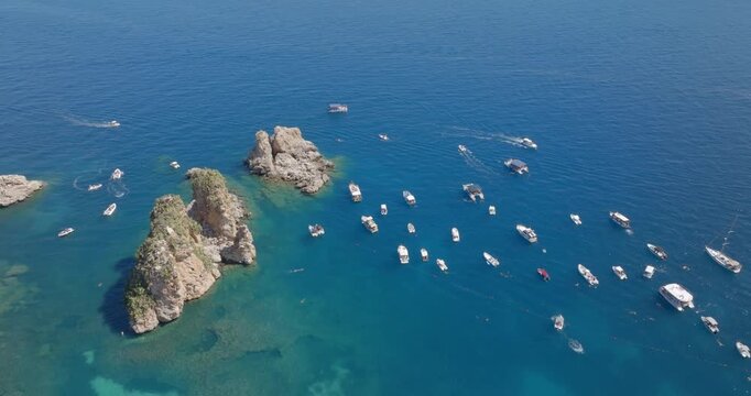 Aerial view of the Faraglioni rocks located in the Bay of Scopello, in the province of Trapani, Sicily, Italy. There are boats on holiday among the cliffs.
