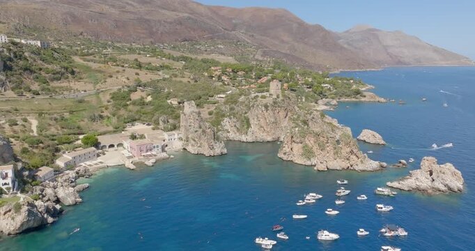 Aerial view of the Bay of Scopello, in the province of Trapani, Sicily, Italy. Boats are on vacation around the rocks in the Zingaro Nature Reserve.