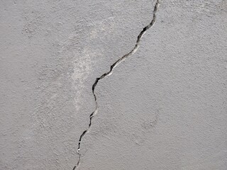 Long deep crack on the damaged concrete wall as texture or background. broken earthquake effect, white grey building cement damage pattern plaster grunge surface 