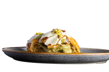 Primer plano de un croissant relleno de crema de pistacho, cubierto con glaseado blanco y trozos de pistacho. Imagen detallada que resalta la textura crujiente del hojaldre y la cremosidad del relleno