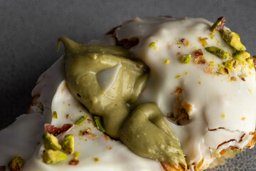 Primer plano de un croissant relleno de crema de pistacho, cubierto con glaseado blanco y trozos de pistacho. Imagen detallada que resalta la textura crujiente del hojaldre y la cremosidad del relleno