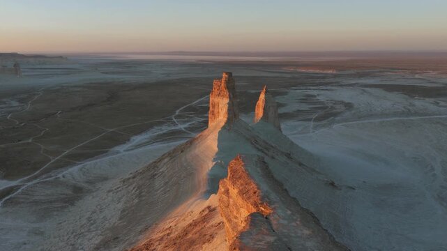 Aerial view of Bozhira's cliffs, casting long shadows across the textured landscape, a blend of light and dark hues, Bozhira, Mangystau Region, Kazakhstan.