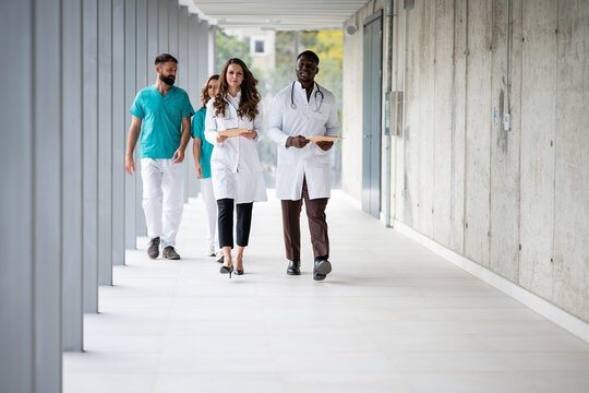Diverse medical team walking in modern hospital corridor