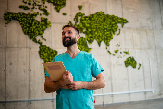 Healthcare professional standing in front of green world map - Powered by Adobe