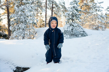 Laughing child plays in snowy winter day, wearing warm clothes, enjoying healthy outdoor activity, joy, and seasonal lifestyle. Nordic Nature